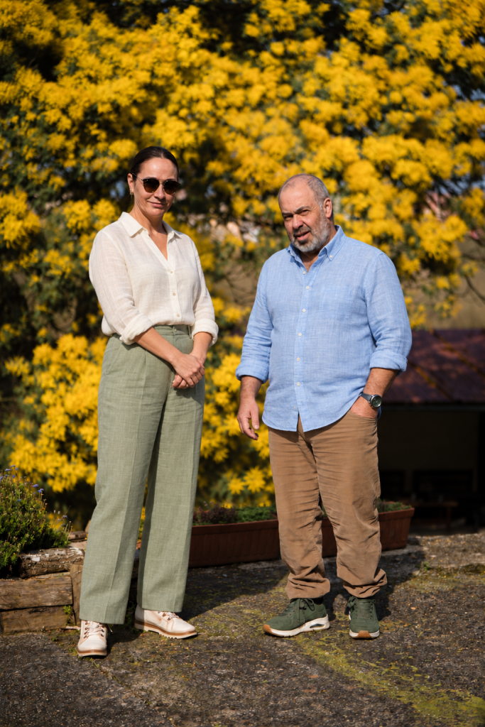 Ana y Carlos, anfitriones de Las Mimosas del Nalón, junto a una mimosa en flor
